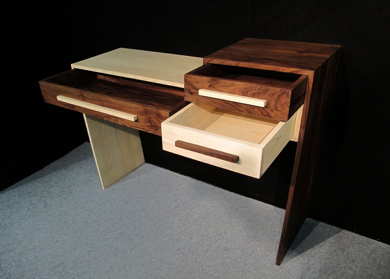Les tiroirs s'ouvrent par le biais de poignées en bois qui suivent les lignes du meuble.